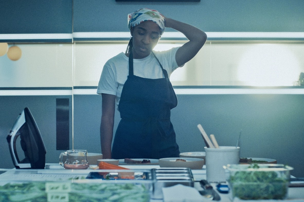 Η Sydney (Ayo Edebiri) στέκεται προβληματισμένη μπροστά από τον πάγκο της κουζίνας του εστιατορίου. Στιγμιότυπο από τη σειρά «The Bear».